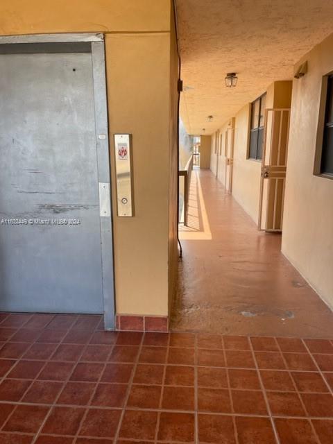 A hallway with tiled flooring leads to an elevator door and a series of apartment entrances — 10145 NW 9th St Cir # 502, Miami FL 33172, MIAMI, FL