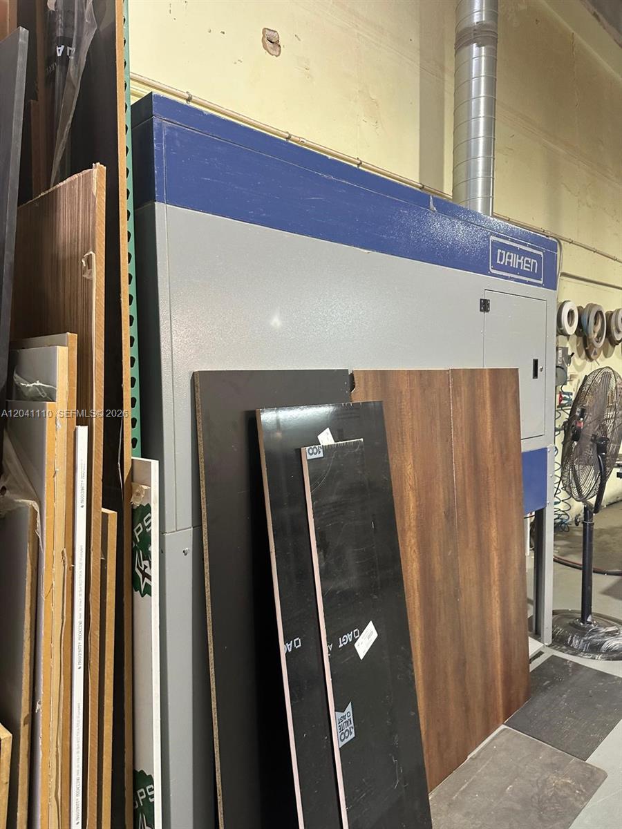 A large industrial Daiken machine stands in a warehouse space filled with stacked wood panels — Cabinet Manufacturing, Hialeah FL 33016, HIALEAH, FL