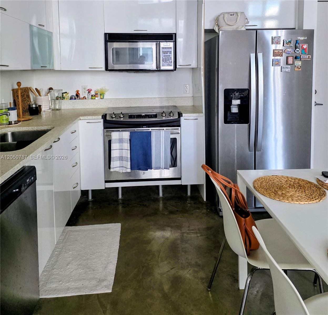 A kitchen features white cabinets, stainless steel appliances, and a concrete floor — 234 NE 3rd St, Miami FL 33132, MIAMI, FL