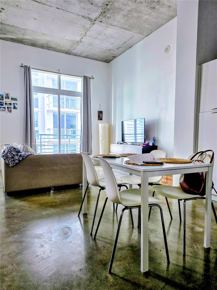 A dining area with white chairs and a table sits before a living room space — 234 NE 3rd St, Miami FL 33132, MIAMI, FL