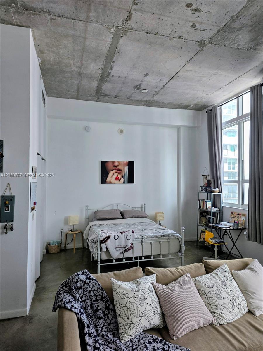 A bedroom with a concrete ceiling, white walls, and a metal bed frame — 234 NE 3rd St, Miami FL 33132, MIAMI, FL