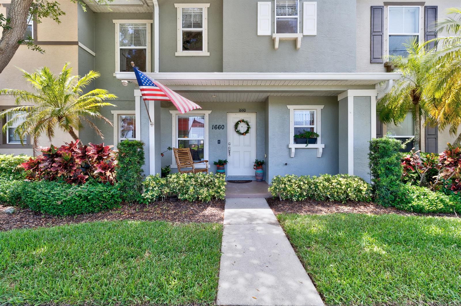 A two-story townhouse exterior features a covered entryway, a front door, and landscaped front yard — 1660 Pointe W Way, Vero Beach FL 32966, VERO BEACH, FL