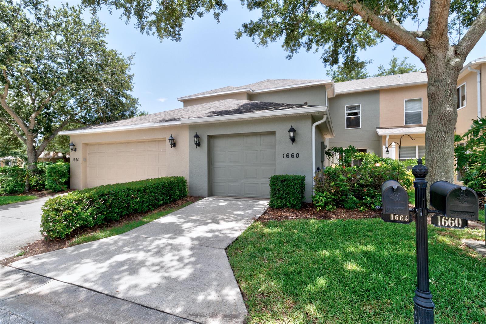 A two-story townhouse exterior features two garage doors, a concrete driveway, and two mailboxes — 1660 Pointe W Way, Vero Beach FL 32966, VERO BEACH, FL