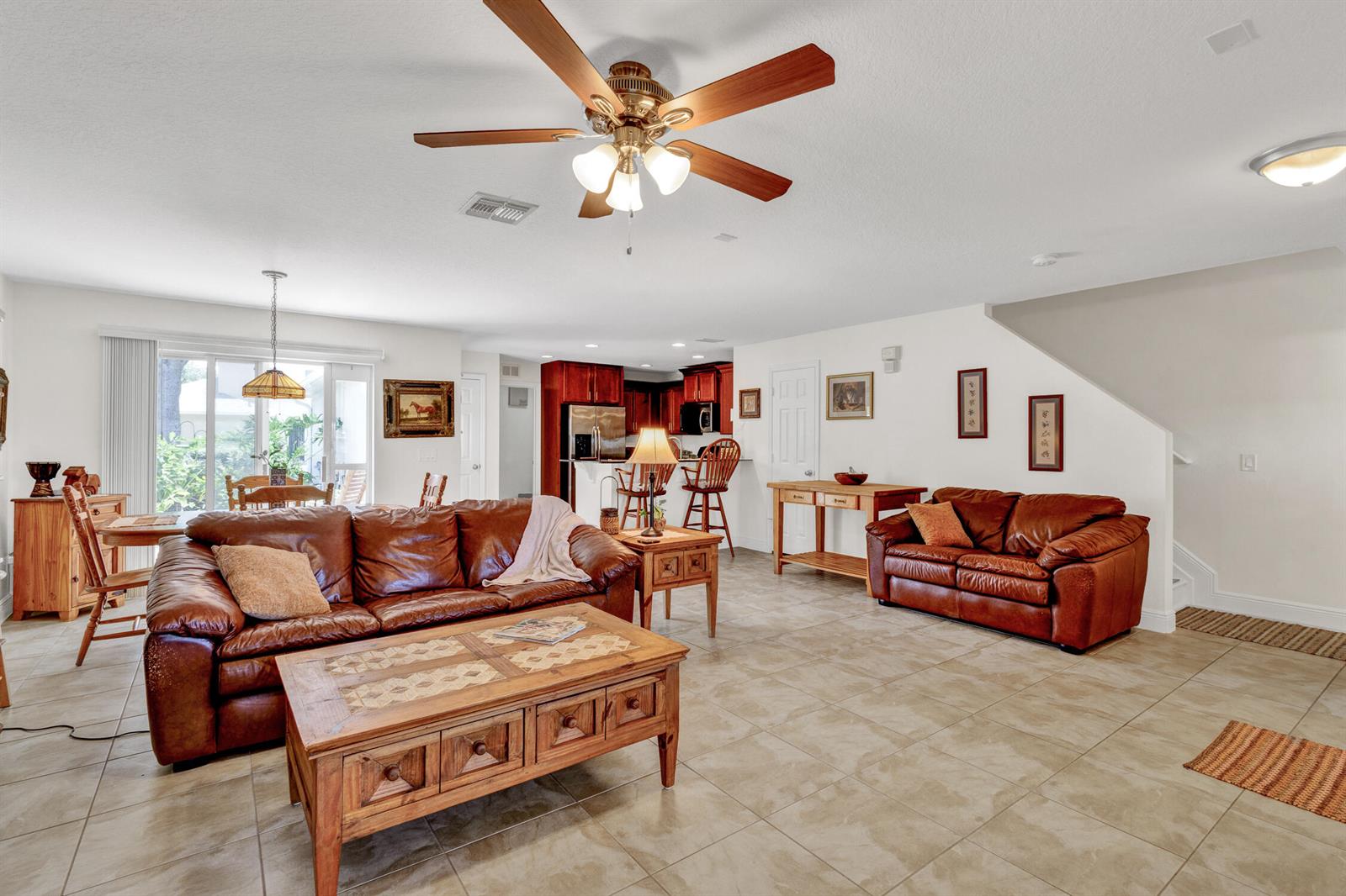 A living room with tile floors, leather sofas, a wooden coffee table, and a ceiling fan — 1660 Pointe W Way, Vero Beach FL 32966, VERO BEACH, FL