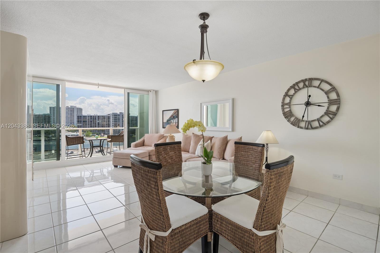 A dining area with a glass table and wicker chairs sits before a living room — 3505 S OCEAN DR # 604, Hollywood FL 33019, HOLLYWOOD, FL