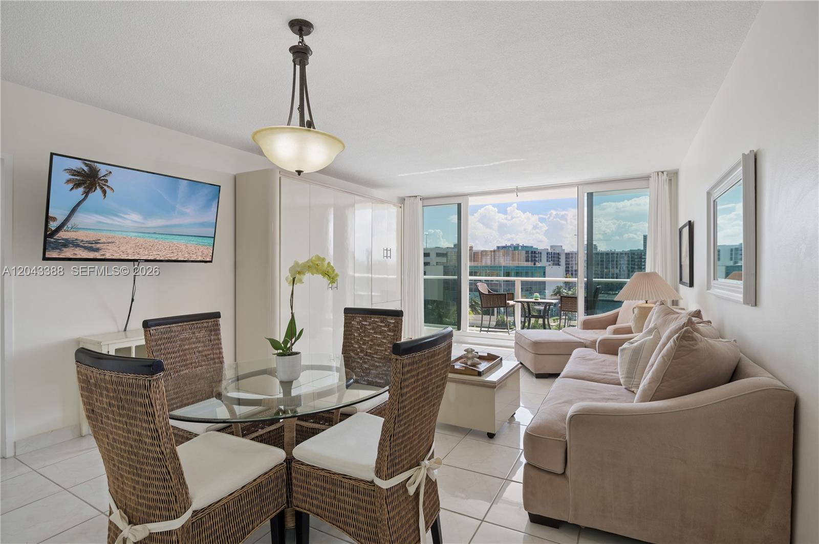 A living and dining area features wicker chairs, a glass table, and a balcony view — 3505 S OCEAN DR # 604, Hollywood FL 33019, HOLLYWOOD, FL