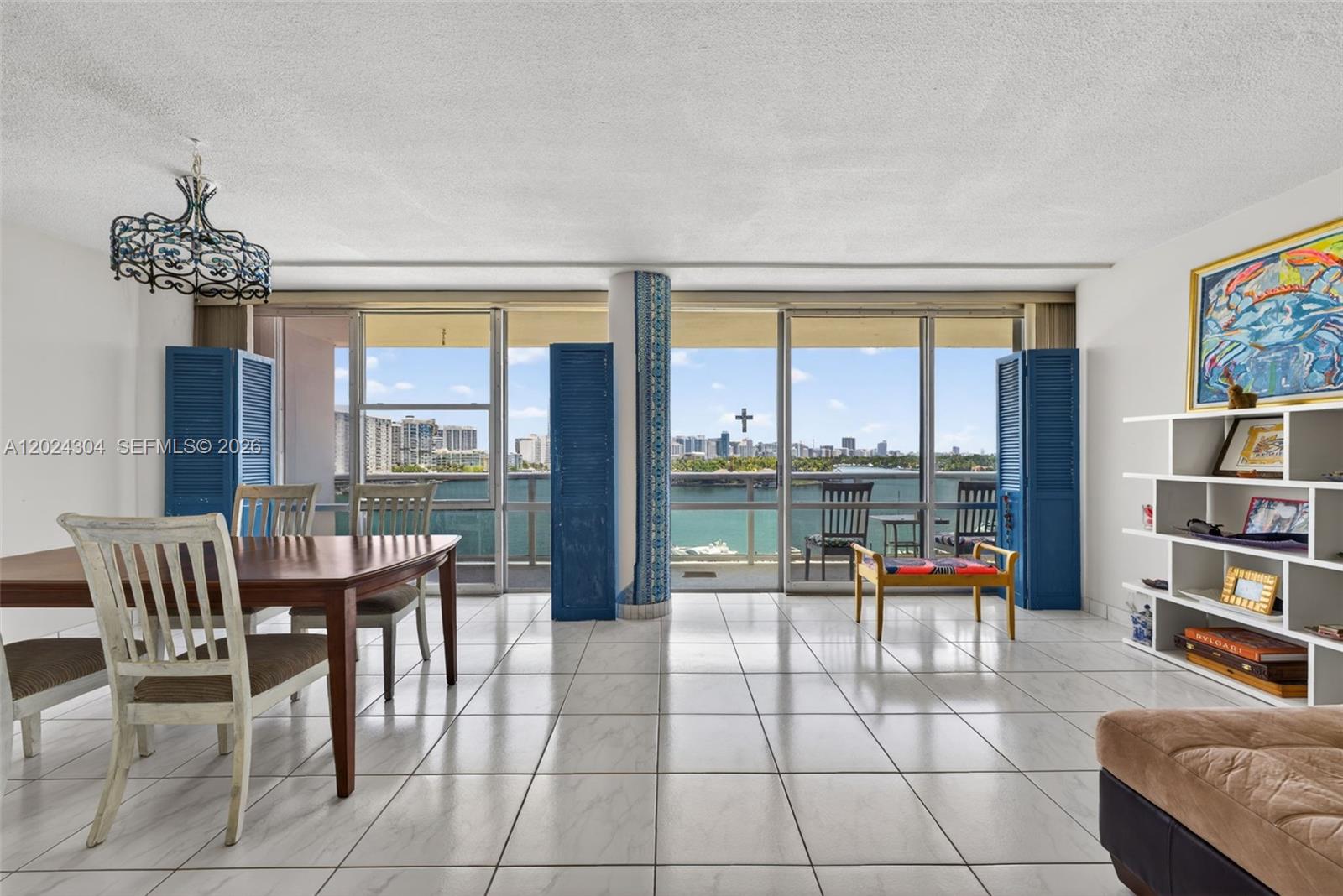 A dining area with tile floors and floor-to-ceiling windows overlooking a waterfront city view — 900 Bay Dr # 606, Miami Beach FL 33141, MIAMI BEACH, FL