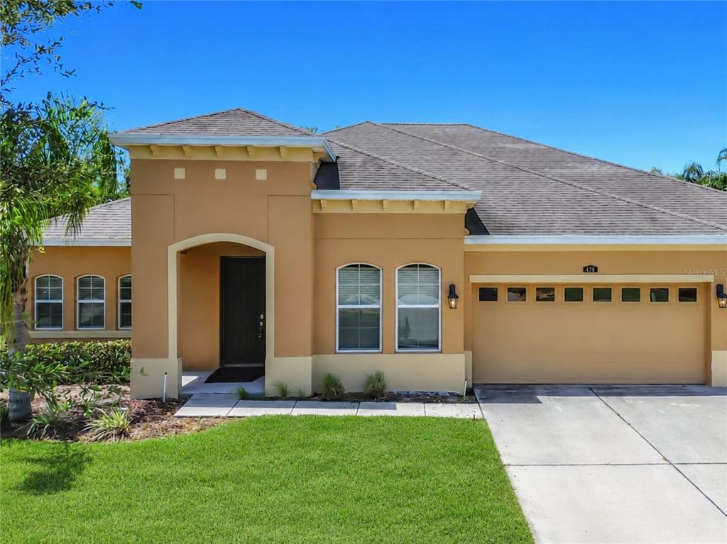 A single-story house with a tan stucco exterior, a two-car garage, and an arched entryway — 428 PALASTRO AVENUE, AUBURNDALE, FL