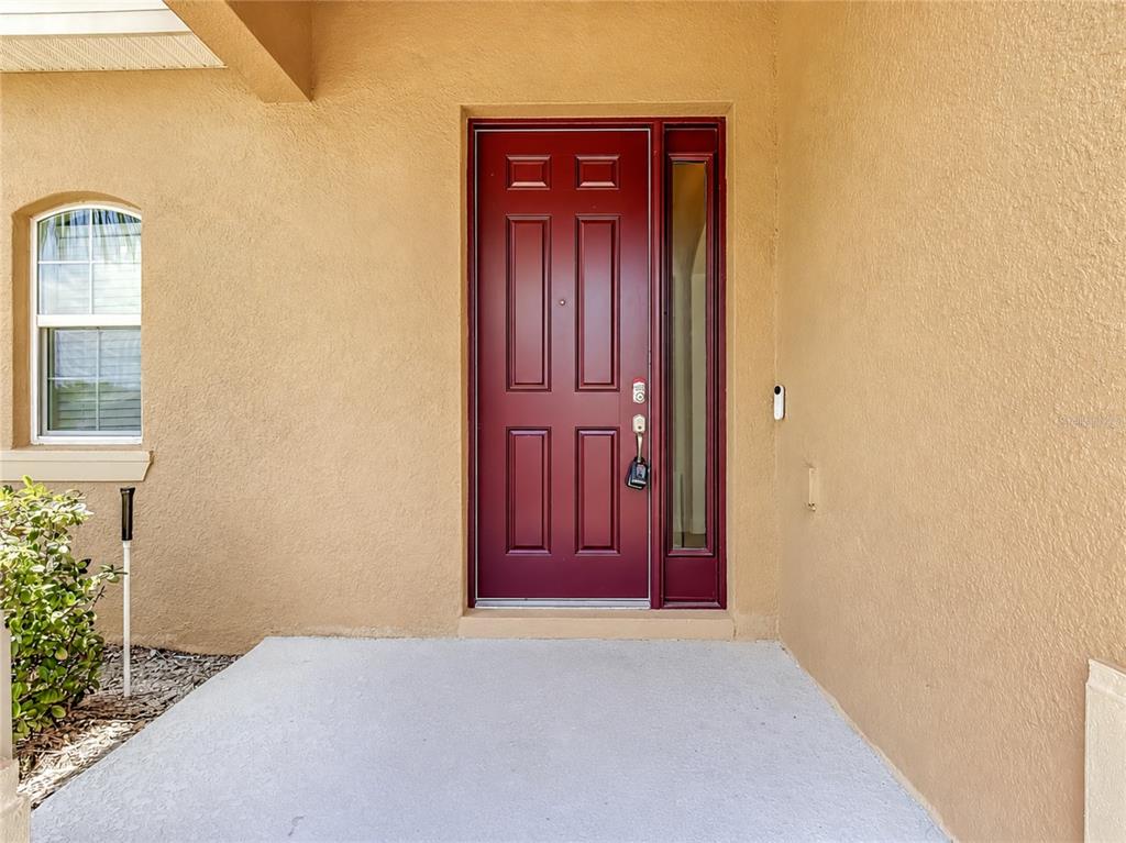 A red front door with a side window is set into a tan stucco exterior — 428 PALASTRO AVENUE, AUBURNDALE, FL