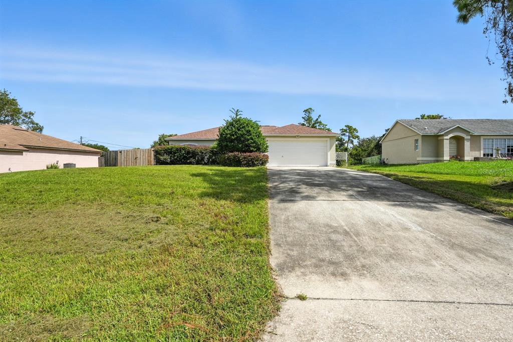 A single-story house with a white garage door and a concrete driveway — 3154 LYNNHAVEN STREET, DELTONA, FL