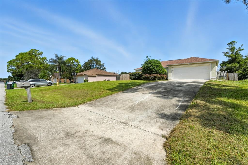 A concrete driveway leads to the garage of a single-story house with a lawn — 3154 LYNNHAVEN STREET, DELTONA, FL