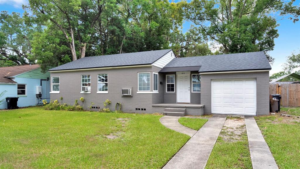 A gray, single-story house with a white front door, attached garage, and a concrete driveway — 1810 HILLCREST STREET, ORLANDO, FL