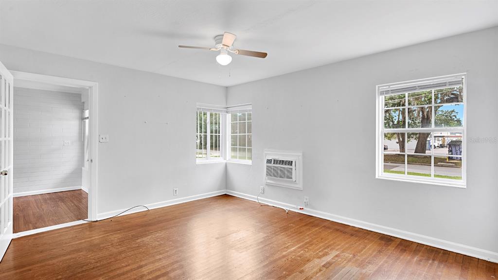 An empty room with hardwood floors, a ceiling fan, a window unit, and two windows — 1810 HILLCREST STREET, ORLANDO, FL