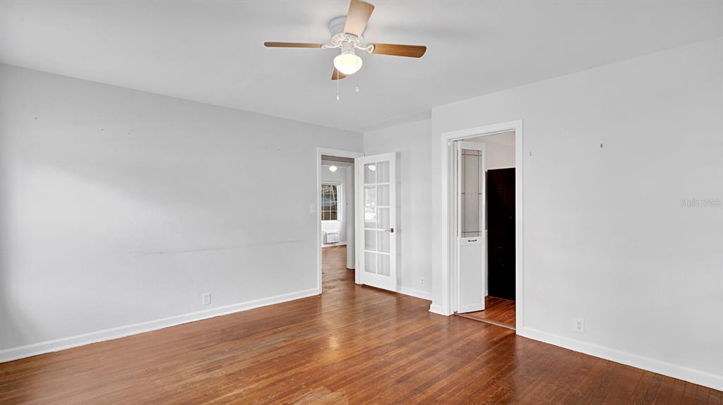 An empty room with hardwood floors, a ceiling fan, and two doorways with glass panels — 1810 HILLCREST STREET, ORLANDO, FL