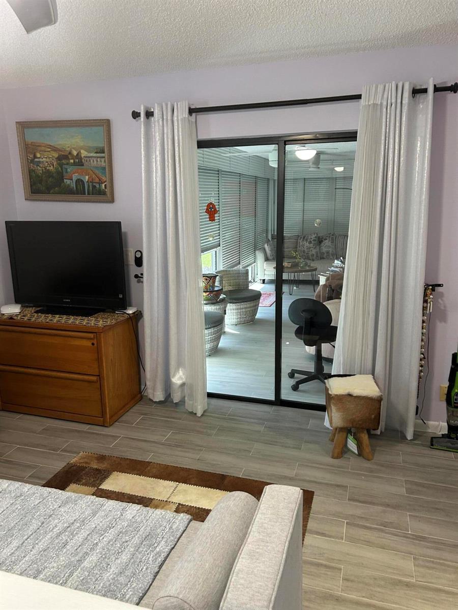 A living room features light-colored tile flooring, a sliding glass door, and a wooden dresser — 10271 N Circle Lake Drive, Boynton Beach FL 33437, BOYNTON BEACH, FL