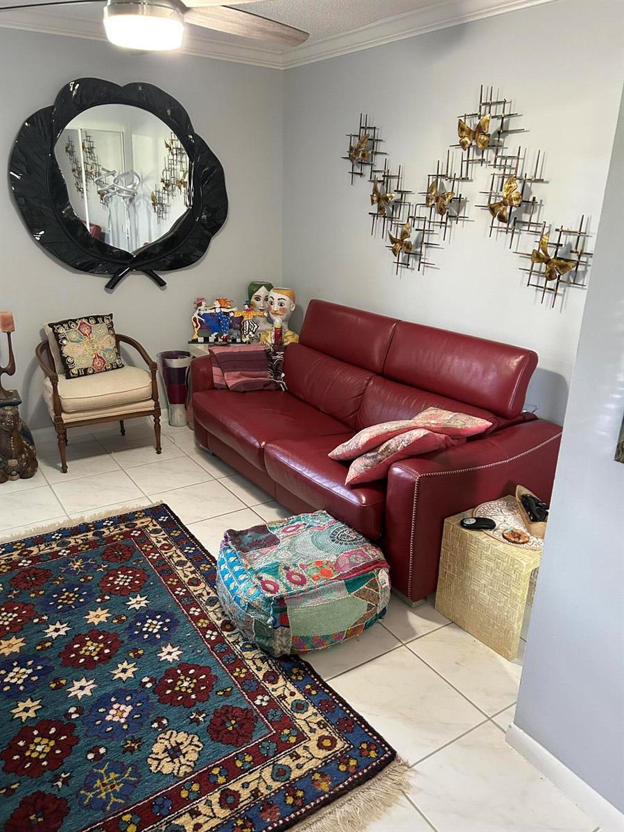 A living room features a red leather sofa, a patterned rug, and wall-mounted metal art — 10271 N Circle Lake Drive, Boynton Beach FL 33437, BOYNTON BEACH, FL