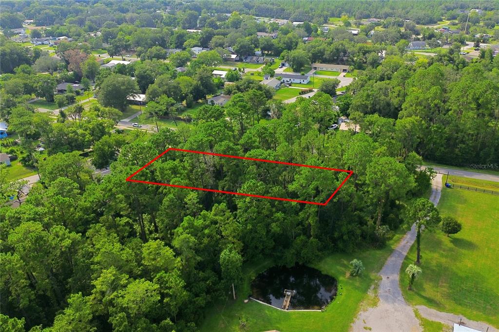 An aerial view shows a rectangular plot of land outlined in red amidst dense trees — 1800 OLD DAYTONA ROAD, DELAND, FL