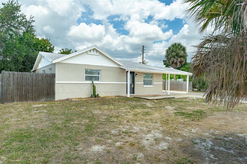A single-story house with a beige brick exterior, white trim, and a covered carport — 6001 CRESTRIDGE ROAD, TAMPA, FL