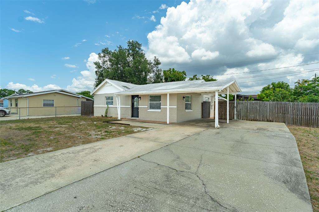 A single-story house with a beige brick exterior, a front carport, and a concrete driveway — 6001 CRESTRIDGE ROAD, TAMPA, FL