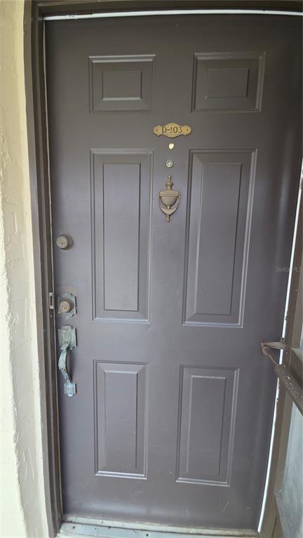 A dark brown front door with a door knocker and unit number D-103 — 100 E KENTUCKY AVE UNIT 103D, DELAND, FL
