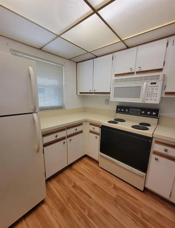 A kitchen features white cabinets, laminate countertops, a white refrigerator, and a black electric stove — 100 E KENTUCKY AVE UNIT 103D, DELAND, FL