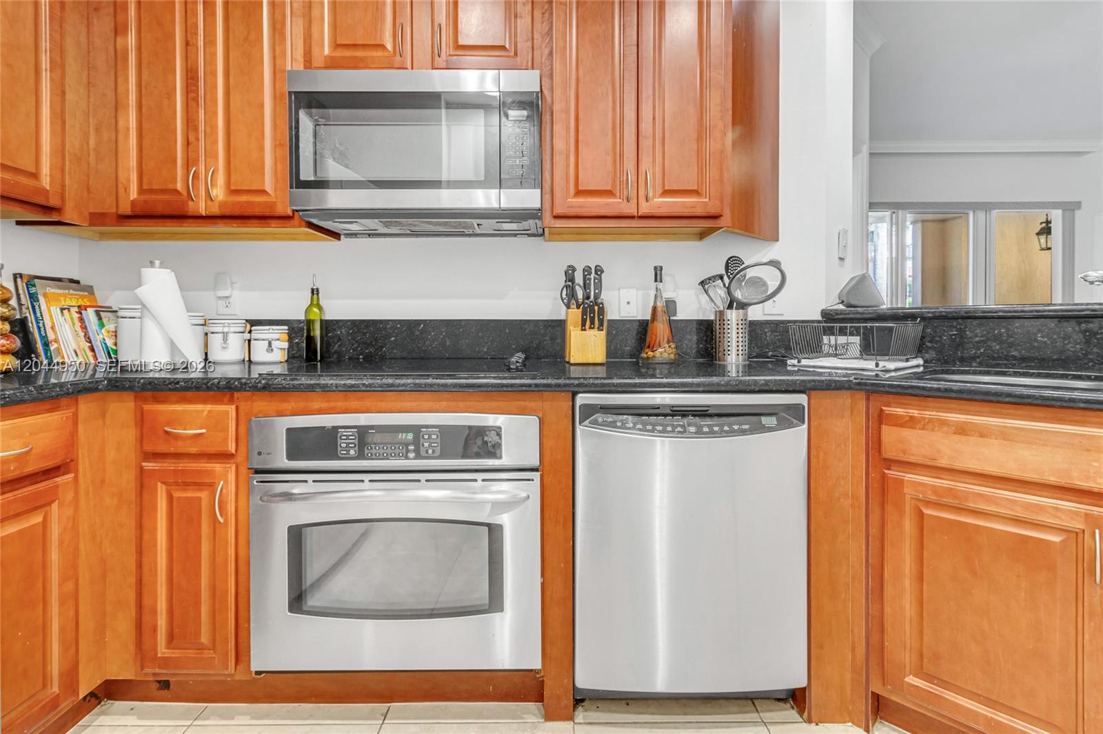 A kitchen features wood cabinets, stainless steel appliances, and a black granite countertop — 16100 Emerald Estates Dr # 298, Weston FL 33331, WESTON, FL