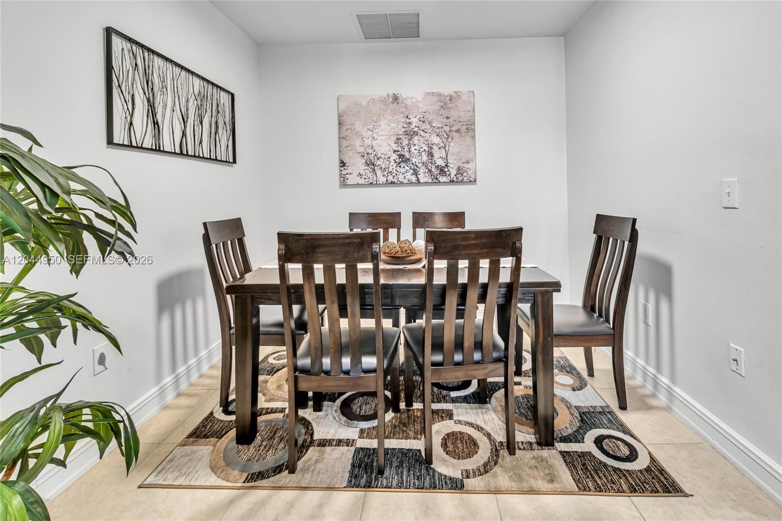 A dining room features a dark wood table and chairs set on a patterned rug — 16100 Emerald Estates Dr # 298, Weston FL 33331, WESTON, FL