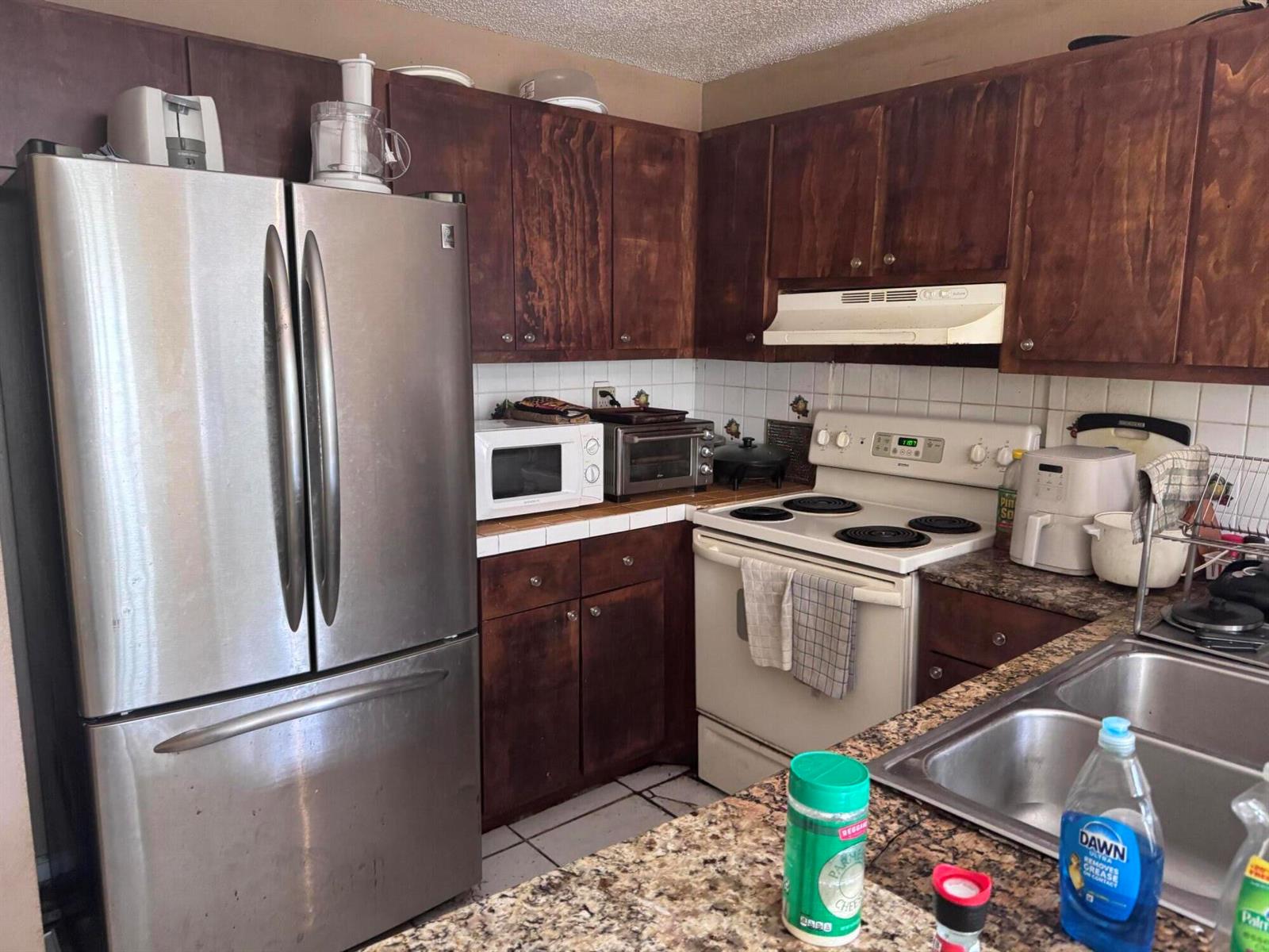 A kitchen features dark wood cabinets, stainless steel appliances, and granite countertops — 4346 NW 4th Avenue, Deerfield Beach FL 33064, DEERFIELD BEACH, FL