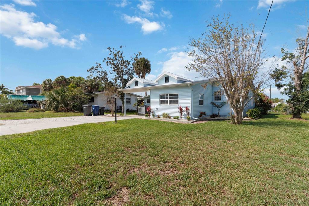 A light blue single-story house with a carport and a large front lawn — 607 MANATEE AVENUE, ELLENTON, FL