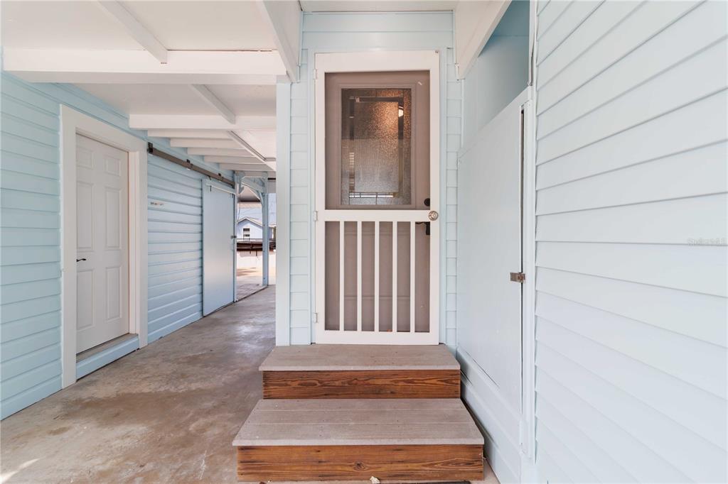 A light blue exterior wall features a screen door leading to two wooden steps — 607 MANATEE AVENUE, ELLENTON, FL