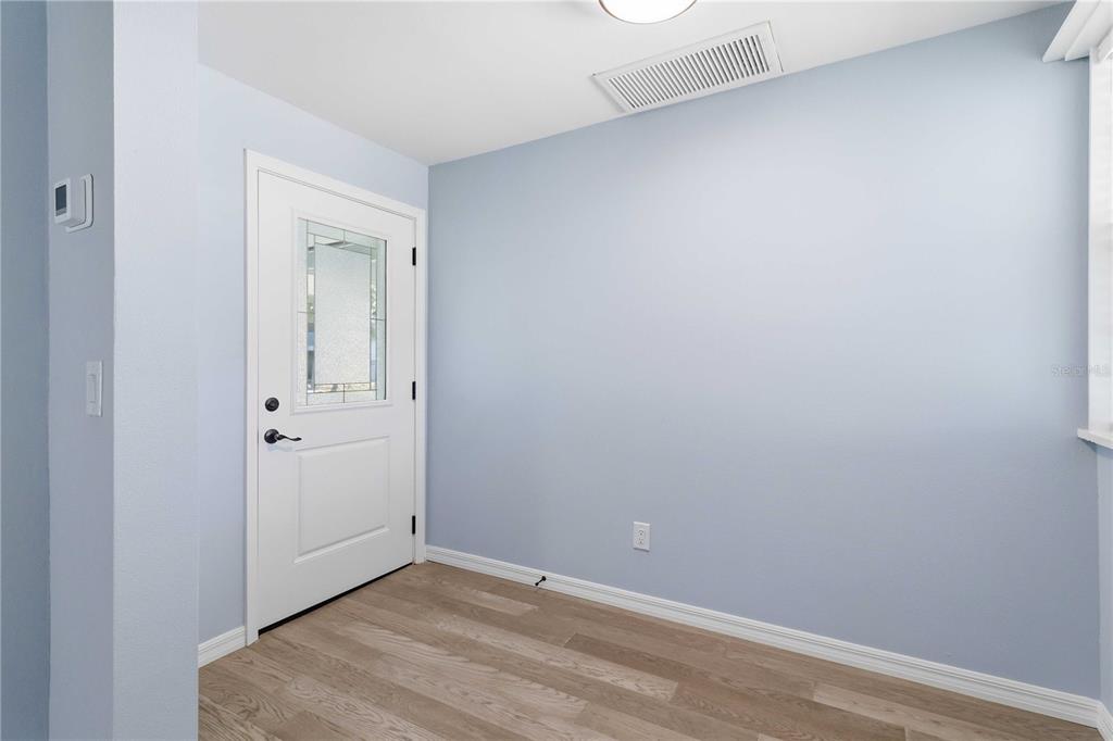 An entryway features light blue walls, wood-look flooring, and a white door with a glass insert — 607 MANATEE AVENUE, ELLENTON, FL