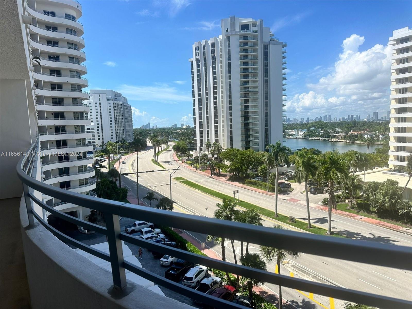 A high-angle view from a balcony overlooks a multi-lane road, palm trees, and tall buildings — 5555 Collins Ave # 8Z, Miami Beach FL 33140, MIAMI BEACH, FL