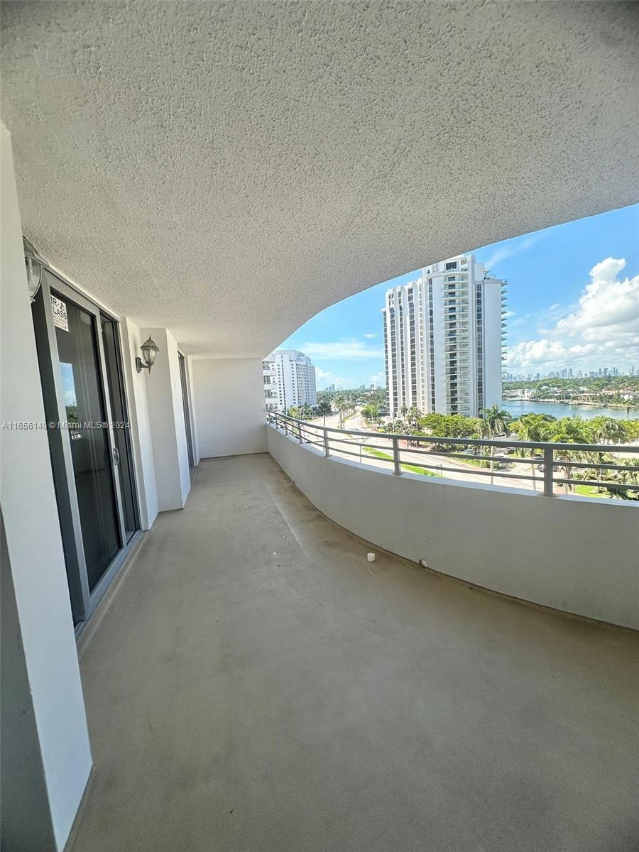 A curved balcony with a concrete floor overlooks a road, water, and high-rise buildings — 5555 Collins Ave # 8Z, Miami Beach FL 33140, MIAMI BEACH, FL