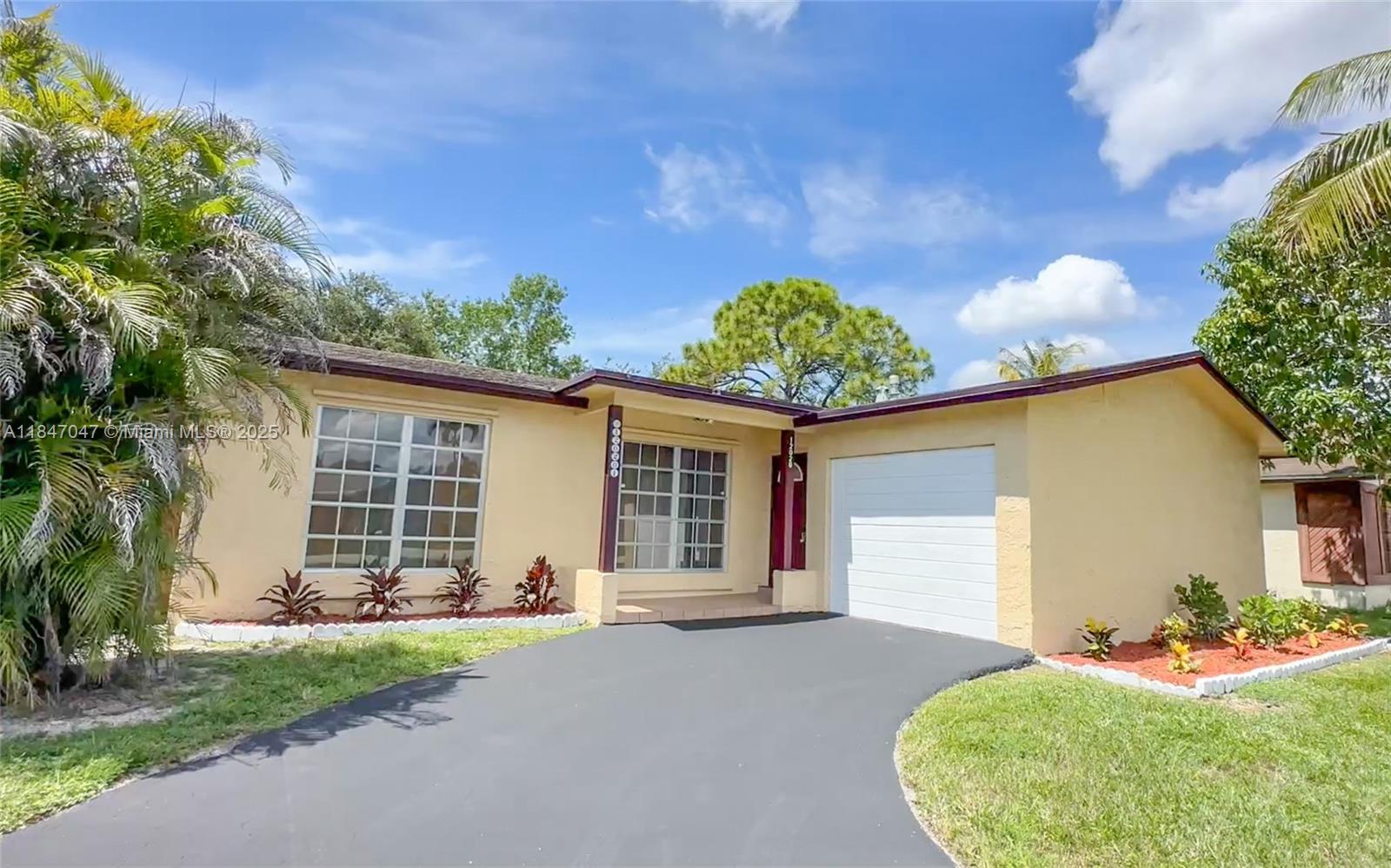 A single-story house with a yellow stucco exterior, a white garage door, and a driveway — 12020 NW 34th Pl, Sunrise FL 33323, SUNRISE, FL