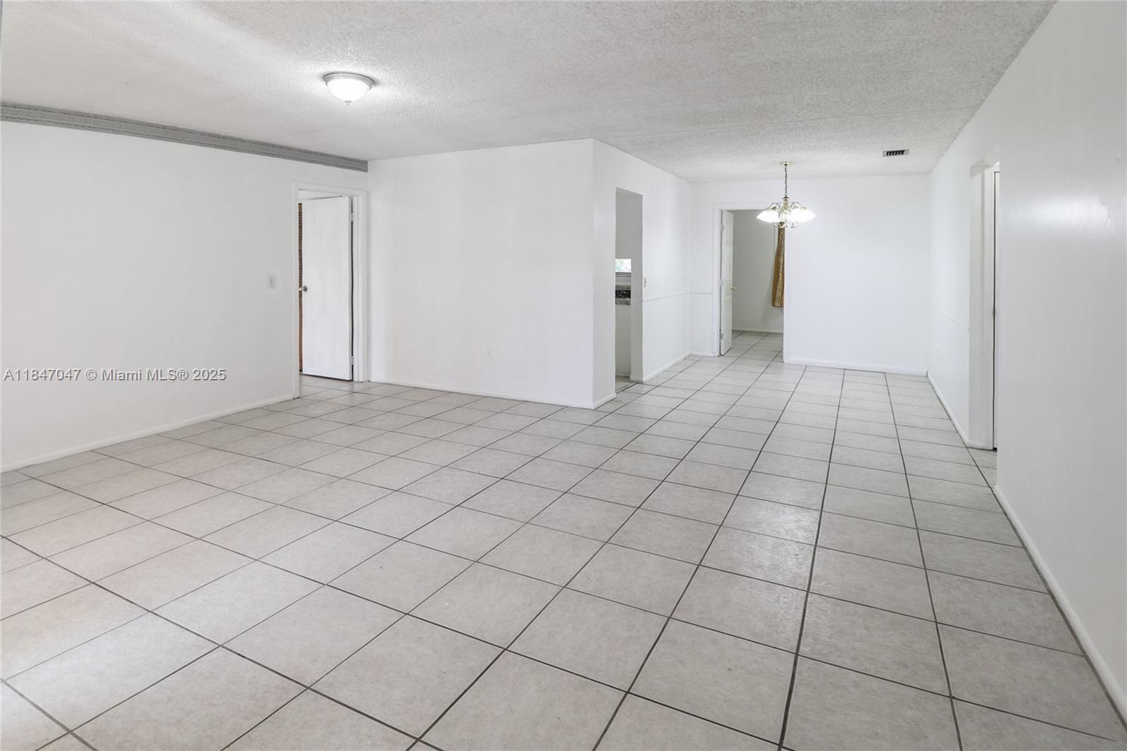 A spacious, white-walled room features light-colored square floor tiles and a central ceiling light — 12020 NW 34th Pl, Sunrise FL 33323, SUNRISE, FL