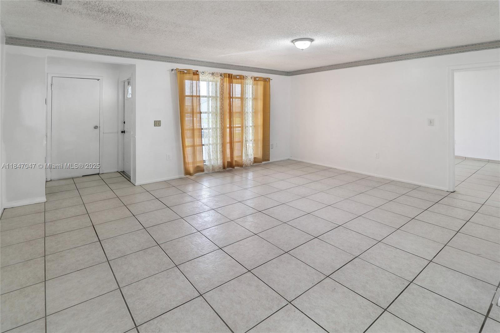 An empty room features white walls, a popcorn ceiling, and light-colored square floor tiles — 12020 NW 34th Pl, Sunrise FL 33323, SUNRISE, FL