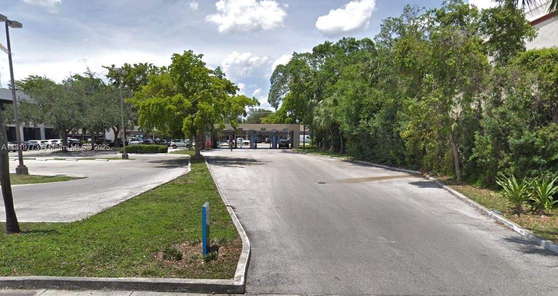 An outdoor view of a paved driveway leading toward a commercial building with drive-thru lanes — 900 NE 125th St, North Miami FL 33161, NORTH MIAMI, FL