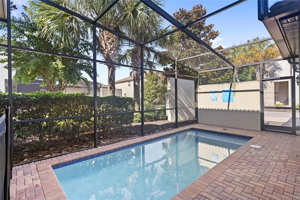 A small rectangular swimming pool sits on a brick patio inside a screened-in enclosure — 2070 ROME DRIVE, KISSIMMEE, FL