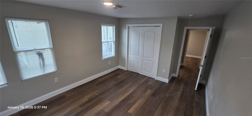 An empty bedroom features wood-look flooring, light gray walls, two windows, and a closet — 603 W 27TH AVENUE, BRADENTON, FL