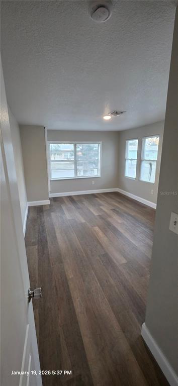 An empty room with wood-look flooring, light-colored walls, and multiple windows — 603 W 27TH AVENUE, BRADENTON, FL