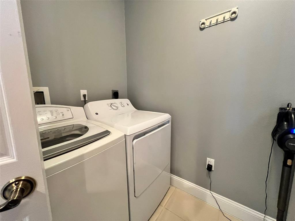 A laundry room features a white top-load washer and dryer against a gray wall — 3608 54TH DRIVE W UNIT 202, BRADENTON, FL