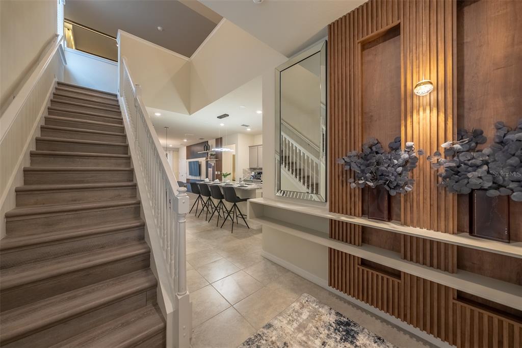 A staircase with wood-look steps leads to an open-concept kitchen featuring a decorative wood-slat wall — 4470 KAIPO ROAD, DAVENPORT, FL