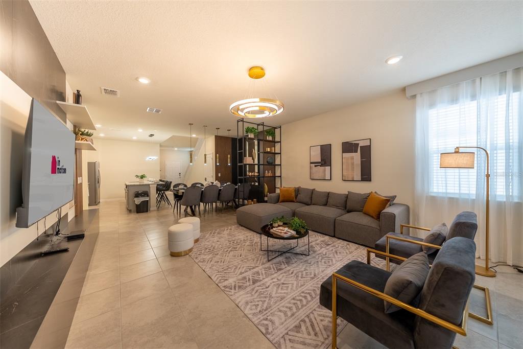 An open-concept living and dining area features tile flooring, a sectional sofa, and modern lighting — 4470 KAIPO ROAD, DAVENPORT, FL