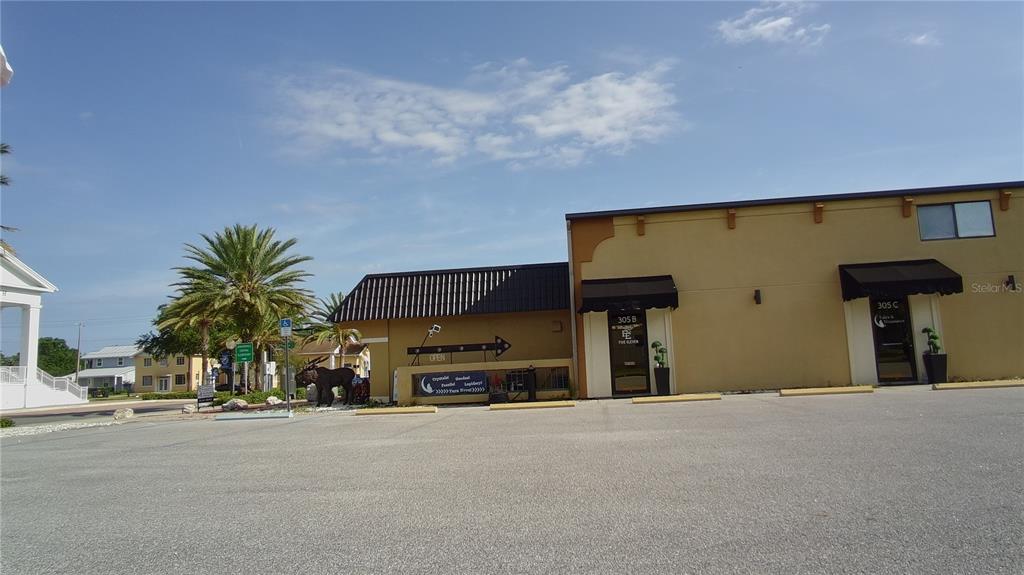 A commercial building exterior features two storefront entrances with black awnings and a parking lot — 305 MAIN STREET UNIT A, B & C, AUBURNDALE, FL