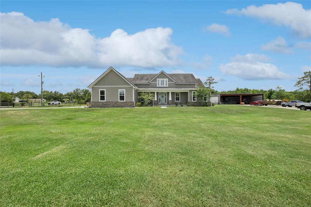 A single-story house with gray siding and stone accents sits on a large grassy lot — 3454 IMPERIAL AVENUE, ST CLOUD, FL