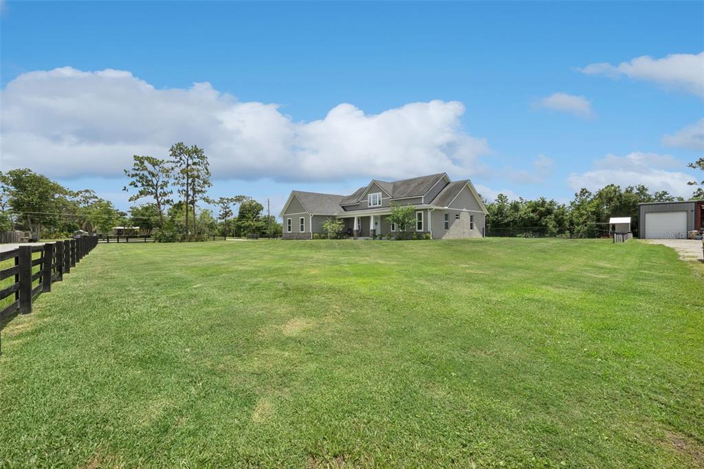 A large house with a gray exterior sits on a vast, grassy rural lot — 3454 IMPERIAL AVENUE, ST CLOUD, FL