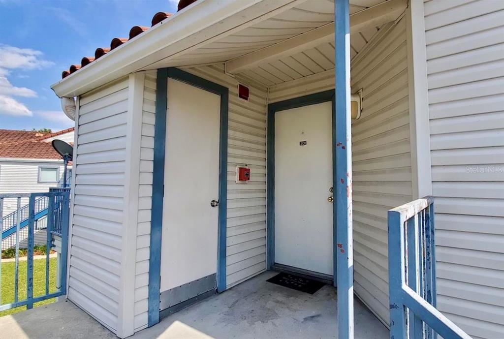 An exterior view of a building entrance featuring two white doors and a metal railing — 2508 WOODGATE BOULEVARD UNIT 201, ORLANDO, FL