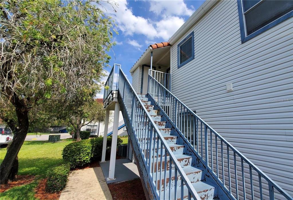 An exterior view of a multi-story building featuring a metal staircase leading to an upper level — 2508 WOODGATE BOULEVARD UNIT 201, ORLANDO, FL