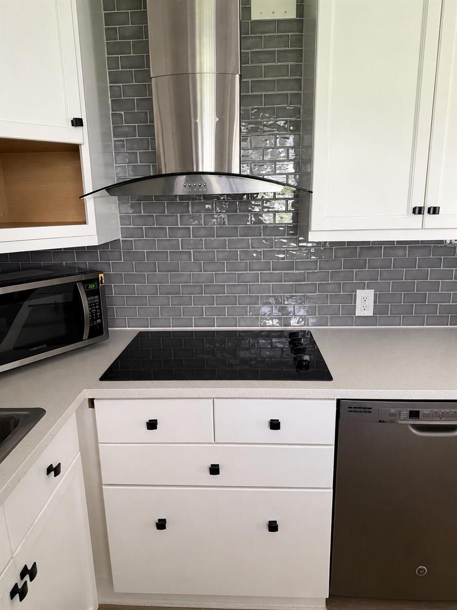 A kitchen features white cabinets, a gray subway tile backsplash, a stainless steel hood, and appliances — 256 Preston G, Boca Raton FL 33434, BOCA RATON, FL