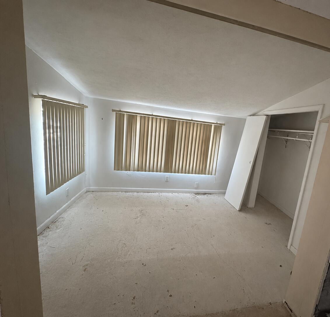 An empty bedroom features white walls, vertical blinds on two windows, and unfinished subflooring — 1781 NW 6th Terrace, Pompano Beach FL 33060, POMPANO BEACH, FL